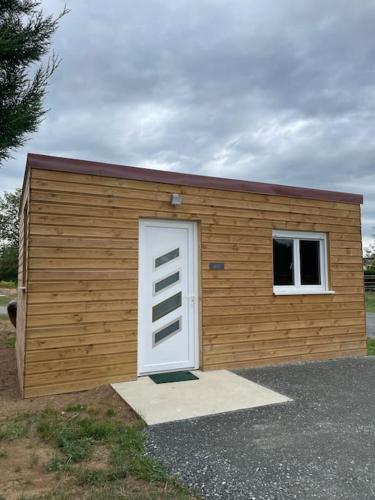 ein kleiner Holzschuppen mit einer Tür und einem Fenster in der Unterkunft Les Chalets du Mancel : Studio June - 24H du Mans - Bouleries Jump - in Parence