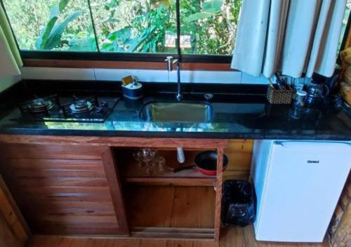 um balcão de cozinha com um lavatório e uma janela em Chalé Silvia Gatto - Suíte Bauru em Núcleo Mauá