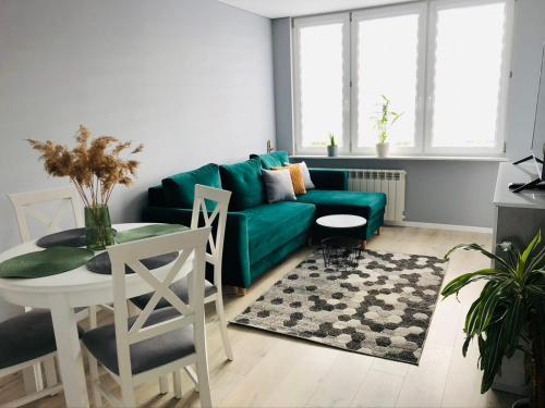 a living room with a green couch and a table at Apartament Panorama miasta in Olsztyn