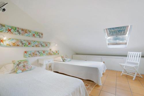 a room with two beds and a chair and a window at Sun and Moon in Porto Santo