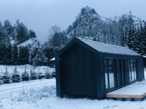 a black shed in the snow with a snow covered field at Chyża Zagroda in Jaworki