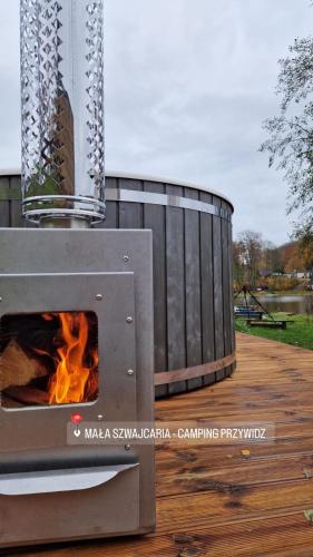 a woodburning stove on a deck with a fire at Camping Przywidz - Mała Szwajcaria in Przywidz