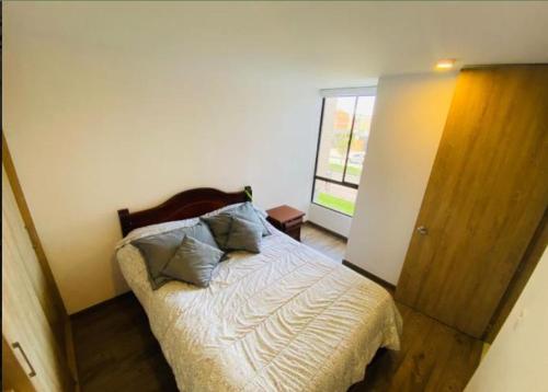 um quarto com uma cama com uma cabeceira em madeira e uma janela em Cipres de la florida em Bogotá
