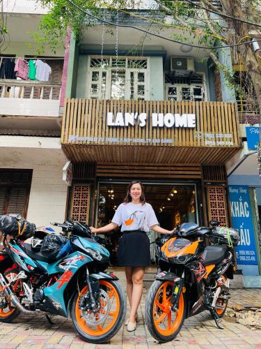 a woman standing between two motorcycles in front of a store at Lan home- Jeep Tour, Motobike tour, rental motobike, private car Cao Bang in Cao Bằng