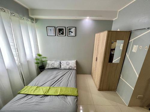 um pequeno quarto com uma cama e um armário de madeira em CebuSureStay Persimmon Studio 535 em Cebu