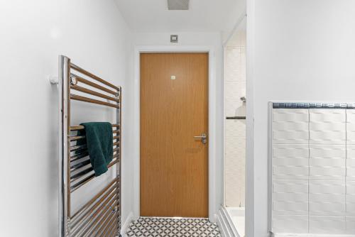 a bathroom with a wooden door and a mirror at Designer Apartment - Great Location! in Manchester