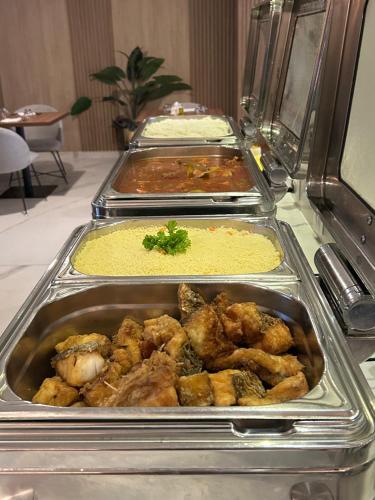 a buffet with several trays of food on a table at Hôtel Ivotel Abidjan in Abidjan