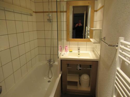 een persoon die een foto neemt van een badkamer met een bad en wastafel bij Appartement 644 au pied des pistes de Belle Plagne in La Plagne Tarentaise