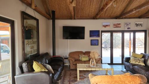 sala de estar con sofás de cuero y TV en Zoutpanputs Game Lodge, en Askham