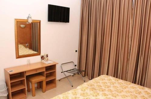 Schlafzimmer mit einem Bett, einem Schreibtisch und einem Spiegel in der Unterkunft Hotel yasmine in Sfax