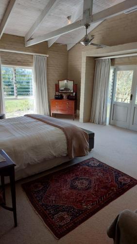 a large bedroom with a bed and a dresser and windows at Hartland Country House Oudtshoorn in Oudtshoorn