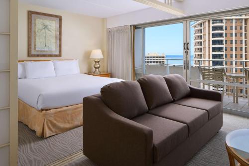 a bedroom with a bed and a couch and a balcony at Ilikai Lite in Honolulu
