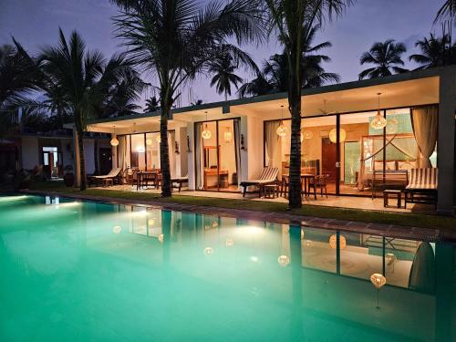 a villa with a swimming pool at night at Sri Palms in Kosgoda