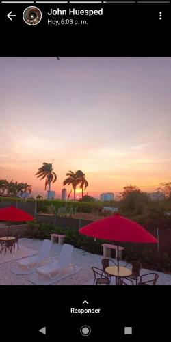 a picture of a sunset with chairs and umbrellas at Hostal Mi Elvirula in Santa Marta