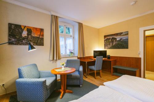 a hotel room with a bed and a desk and chairs at Gästehaus am Kurpark in Bad Schandau