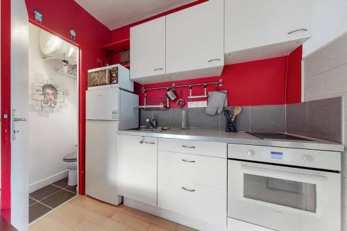 - une cuisine avec des placards blancs et des murs rouges dans l'établissement 2 pièces Lumineux & Calme (28m²), à Paris