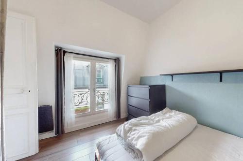 une chambre avec un lit et une grande fenêtre dans l'établissement 2 pièces Lumineux & Calme (28m²), à Paris
