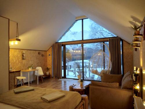 a bedroom with a bed and a large window at Kazbegi cottages qabarjina in Kazbegi