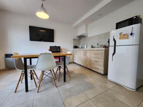 a kitchen with a table and a white refrigerator at Casa de Campo Flor Dorada in Centenario