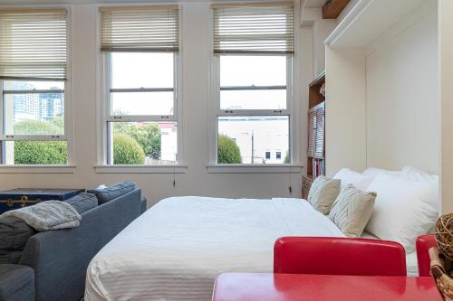 a bedroom with a bed and a couch and windows at Modern Heritage Studio With Murphy Bed in Victoria