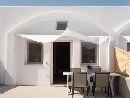 a white patio with a table and chairs under an umbrella at Villas Scirocco in Fira
