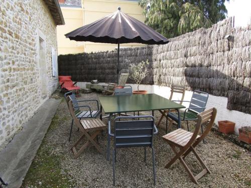 una mesa y sillas con sombrilla en un patio trasero en L'ENVOLEE, en Champdeniers