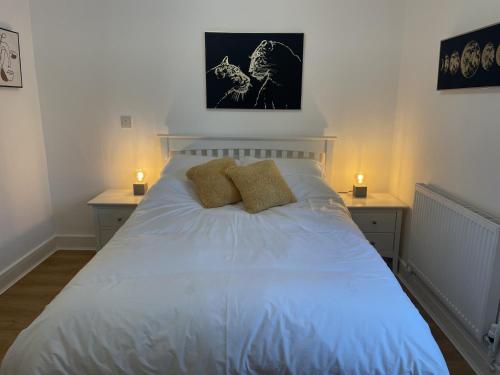 a bedroom with a white bed with two night stands at Modern The Mews Apartment in Bury Saint Edmunds