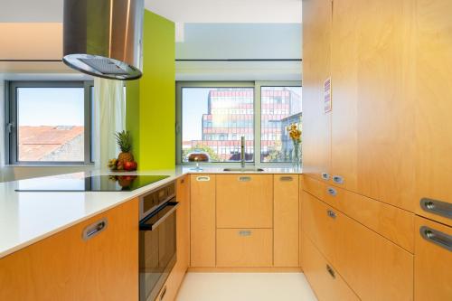 a kitchen with wooden cabinets and green walls and windows at Host Wise - Restful Minimalist Flat - Balcony in Porto