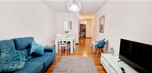 a living room with a blue couch and a dining room at Ocean Pearl Apartment V in Funchal