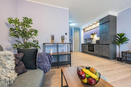 a living room with a couch and a bowl of fruit on a table at Glow Apartments, Apartamenty Nowa Letnica in Gdańsk