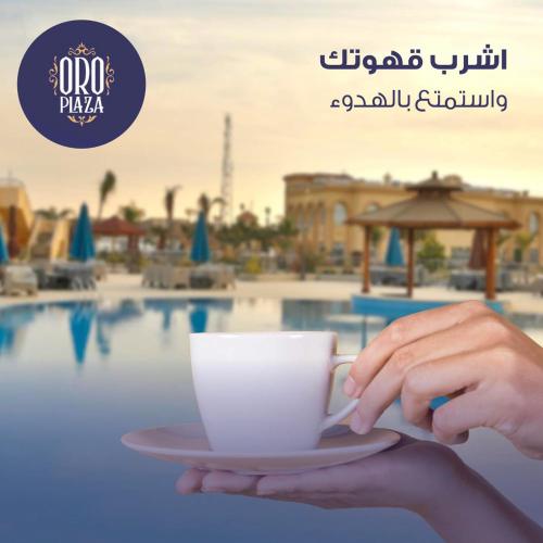 a person holding a cup of coffee in front of a pool at فندق أورو بلازا ORO Plaza Hotel in Cairo