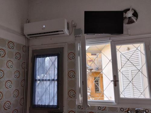 Habitación con espejo y TV por encima de una ventana. en Ήσυχο σπίτι στο Μικρολίμανο, en Pireo