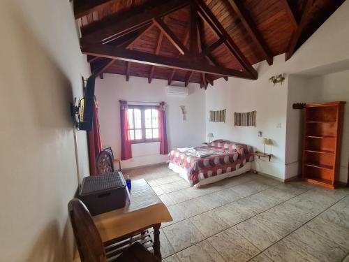a bedroom with a bed and a table and a window at Cabanas Las Pencas, HOSTERIA in Mina Clavero