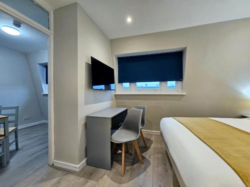 a hotel room with a bed and a desk and a window at BOKA Earls Court in London