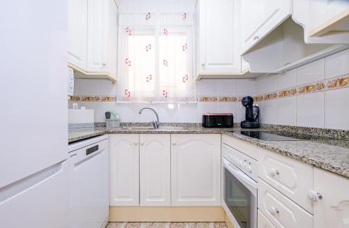 una cucina bianca con mobili bianchi e un lavello di Home&Holiday Goleta with parking-option a Torrevieja