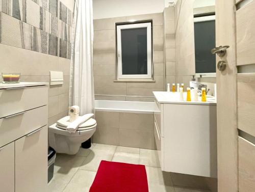 a bathroom with a toilet and a tub and a sink at Bella Vista Red Apartment in Braşov
