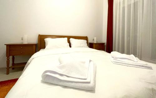 a white bed with white towels on top of it at Bella Vista Red Apartment in Braşov