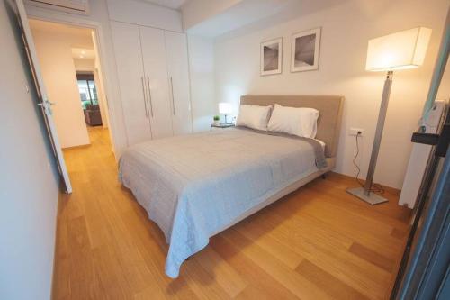 a bedroom with a bed and a lamp on a wooden floor at Voula Luxury Apartment in Athens