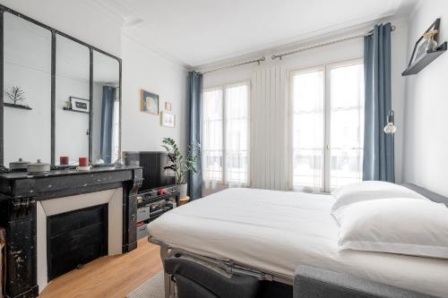 une chambre avec un lit et une cheminée dans l'établissement Veeve - Batignolles Blues, à Paris