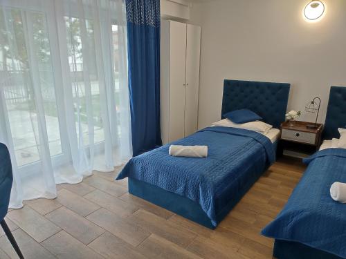 ein Schlafzimmer mit einem blauen Bett und einem Fenster in der Unterkunft Apartament LoftyDream in Mielec