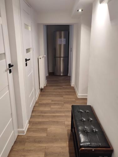 a hallway with a black leather bench and a refrigerator at Apartament LoftyDream in Mielec