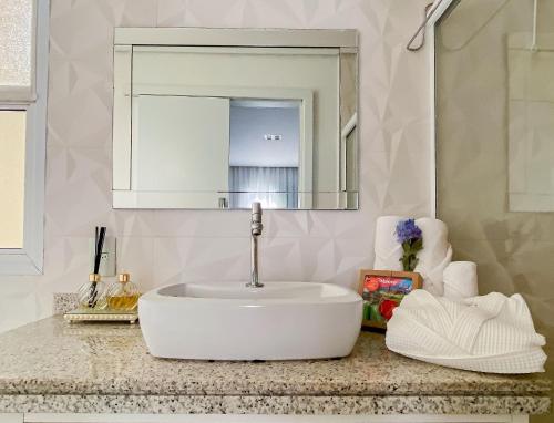 a bathroom with a white sink and a mirror at Lindo Apto Riviera de São Lourenço Mod 3 in Riviera de São Lourenço
