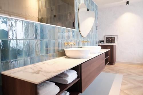 La salle de bains est pourvue de 2 lavabos et d'un miroir. dans l'établissement Boutique Hotel Blendin Bloemendaal aan Zee, à Overveen
