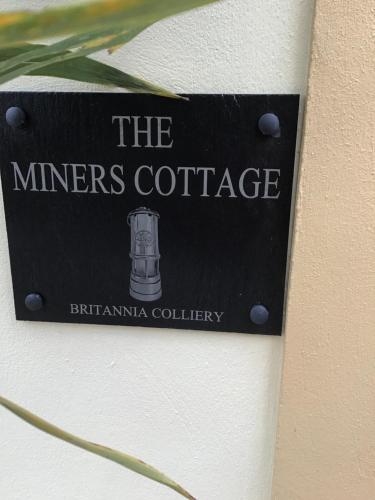 a sign for the minners cottage on a wall at The Miners Cottage in Blackwood