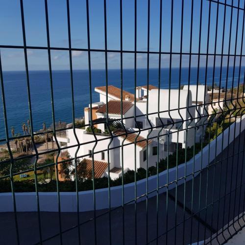 a view of a white house through a fence at Apartamento frente al mar con parking privado in Torrox