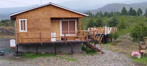 a small wooden cabin with a porch and a balcony at Cabañas y Tinajas FERISI in Cochrane