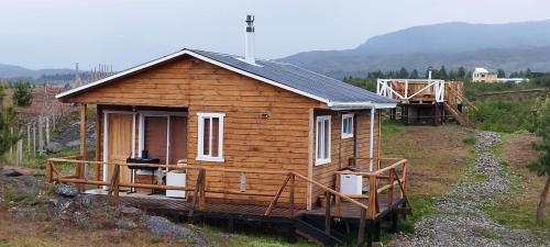 una pequeña casa de madera con un porche en un campo en Cabañas y Tinajas FERISI, en Cochrane