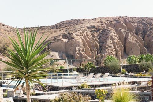 a resort with chairs and a rock formation at Villas Scirocco in Fira