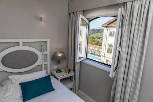 a bedroom with a bed and a large window at Grande Hotel das Caldas da Felgueira in Caldas da Felgueira