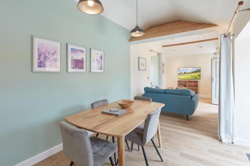 a dining room with a table and a blue couch at Hayes Farm - 8 Houses in Gloucester